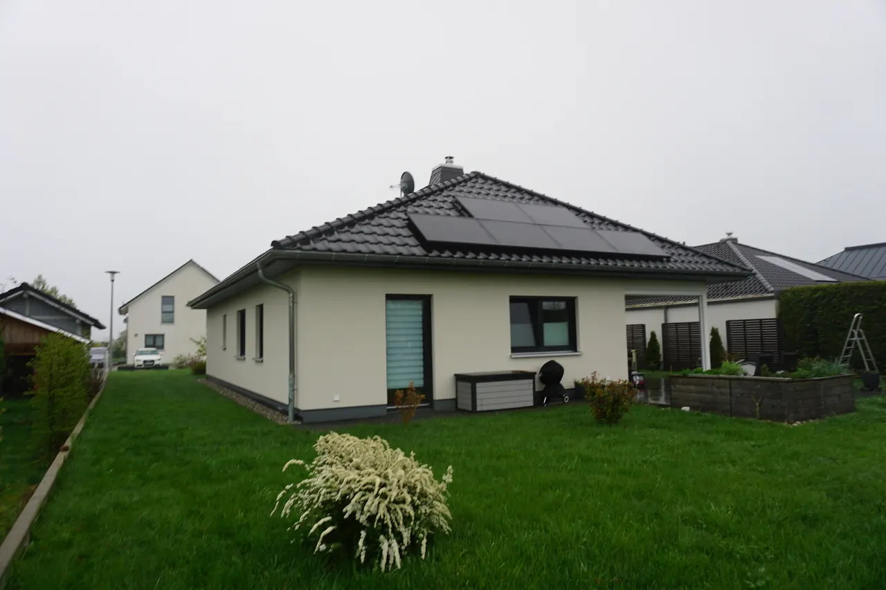 Gartenseite der Außenanlage mit gepflastertem Weg und Beetflächen