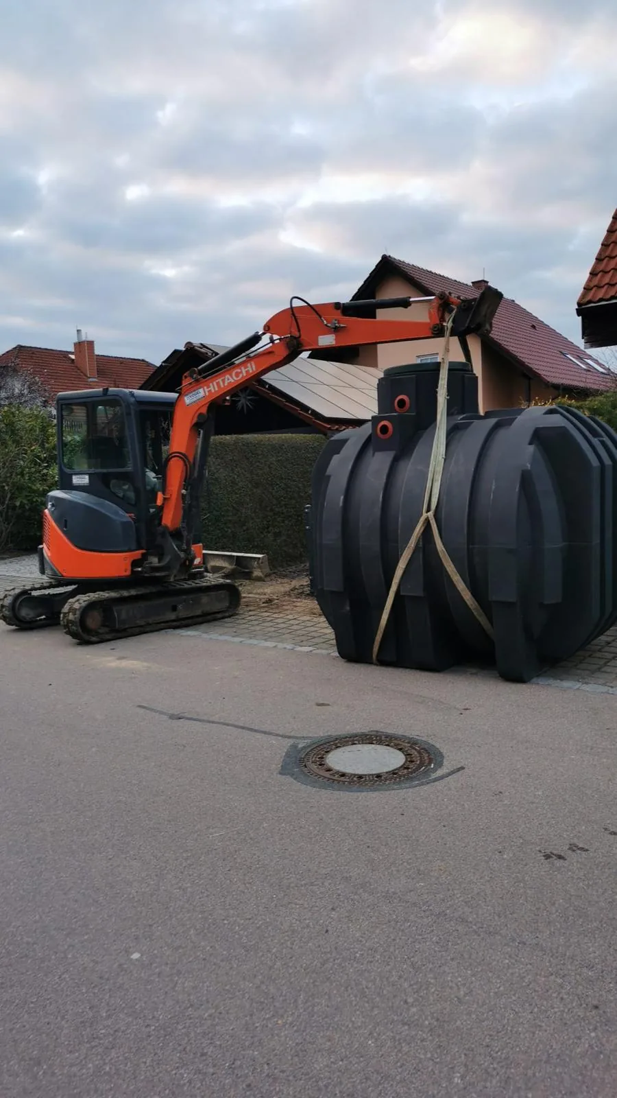 Neue Zisterne, angeschlagen am Bagger, bereit zum Einheben in die Baugrube