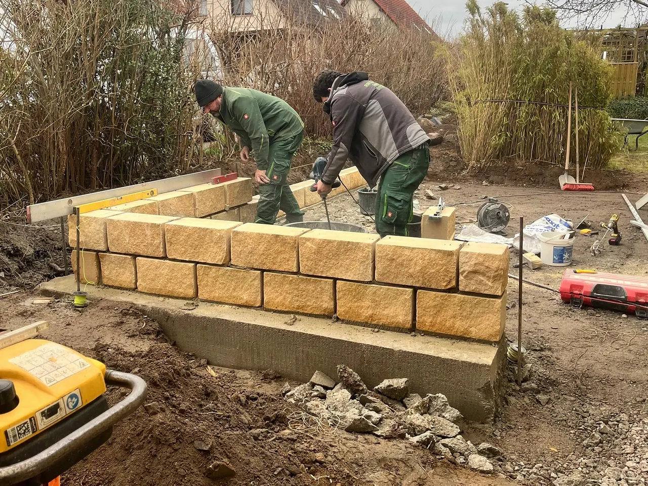 Sandsteinmauer im Bau, Mitarbeiter setzen die Steine