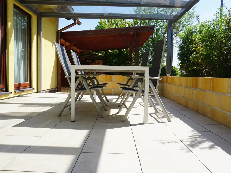 Überdachte Terrasse mit Gartenmöbeln als fertige Außenanlage